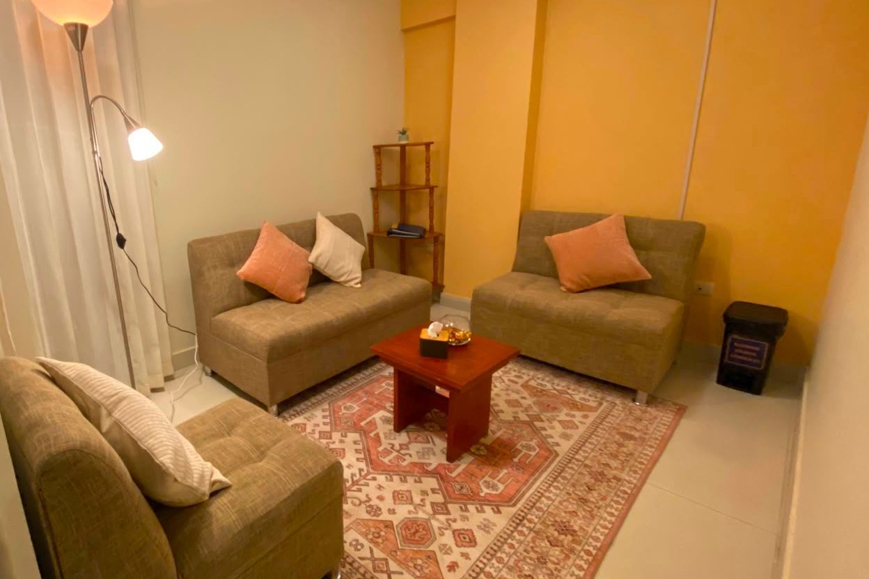 Consultorio de Eutimia con sillones beige, alfombra de diseño andino y pared amarilla